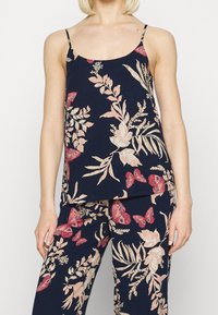 Ensemble de pyjama floral avec un fond bleu marine et un motif de fleurs roses et crème ainsi que de papillons. Tissu léger, bretelles spaghetti.