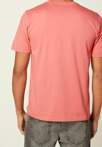 Męska koszulka z krótkim rękawem w jasnym koralowym kolorze, wykonana z miękkiego, gładkiego materiału. Posiada klasyczny okrągły dekolt i regularny krój.