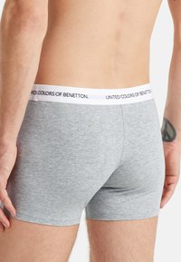 Boxer short in cotone grigio con elastico bianco su cui è stampato in nero 'UNITED COLORS OF BENETTON'. Tessuto morbido, design aderente.