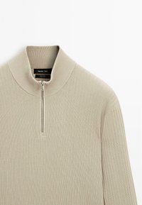 Beige ribbed sweater with a high collar and a front half-zipper. Soft cotton material with textured detailing for added warmth.