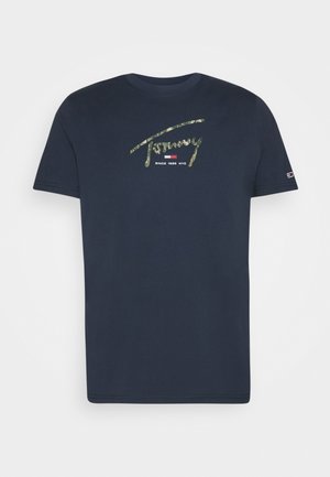 Marineblauw T-shirt met korte mouwen met groene camo-stijl "Tommy" tekst, een rood, wit en blauw logo, en "Since 1985 NYC" eronder op de borst.