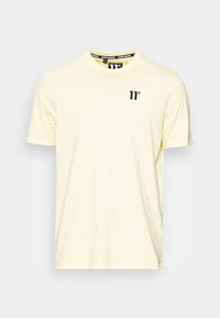 Světle žluté tričko s krátkým rukávem vyrobené z bavlny, s kulatým výstřihem a malým černým logem "11°" na hrudi.