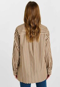 Bruine en crèmekleurige gestreepte longsleeve shirt met knoopmanchetten en een gebogen zoom, met een relaxte pasvorm en een zachte stofstructuur.
