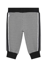 Jogging en noir et blanc à motifs avec une texture en maille, dotés d'une taille noire et de bandes sur les côtés. Les poignets aux chevilles complètent le design.