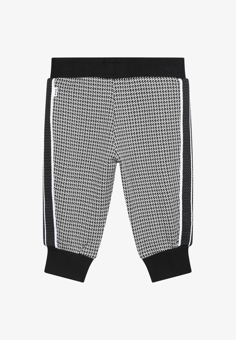 Jogging en noir et blanc à motifs avec une texture en maille, dotés d'une taille noire et de bandes sur les côtés. Les poignets aux chevilles complètent le design.