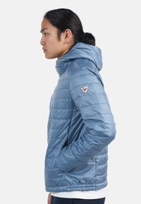 Giacca imbottita azzurro chiaro con cappuccio, con motivo a righe orizzontali, una patch con il logo sul braccio sinistro e polsini elastici.