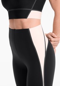 Leggings taille haute noirs et rose clair avec un design color block, des coutures contrastantes, et un tissu lisse et extensible.