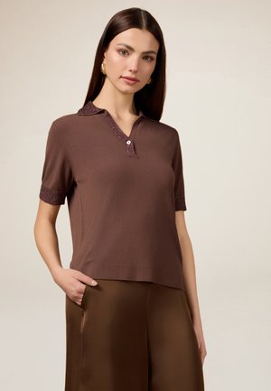 Polo en tricot marron avec un col et des poignets texturés. Doté de manches courtes, d'une patte de boutonnage et d'une coupe décontractée. Tissu au toucher lisse.