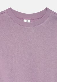 Lavendel crewneck sweatshirt med en jämn textur, med en ribbad krage. Etikett synlig med "GAP" tryckt i en enkel font.