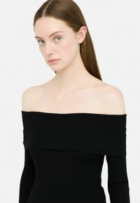 Top nero a costine con spalle scoperte, caratterizzato da maniche lunghe e un ampio scollo, realizzato in un tessuto elasticizzato testurizzato.