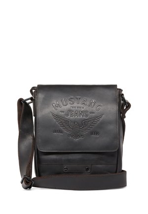 Sac en bandoulière en cuir marron avec logo "Mustang Jeans" en relief, fermeture à pression, bandoulière réglable, texture lisse et design minimaliste.