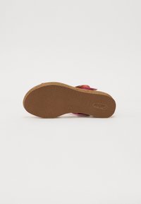 Roze sandaal met een gestructureerde rubberen zool en een kurken tussenzool. Heeft een verstelbare band voor een veilige pasvorm. Glad bovenmateriaal.