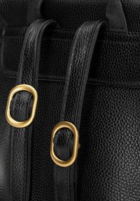 Sac en cuir noir texturé avec deux poignées noires lisses, présentant des accents en métal doré qui forment des anneaux ovales.