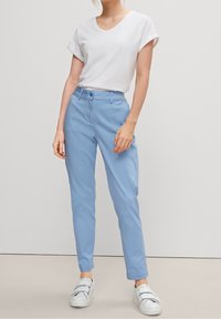 Ljusblå chinos med slim fit, med knäppning, bälteshällor och en slät textur. Matchas med en vit t-shirt med kort ärm.