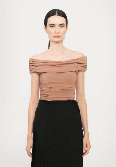 Haut marron à épaules dénudées avec texture froncée, design ajusté, manches courtes, associé à une jupe noire fluide, tissu lisse et subtil éclat.