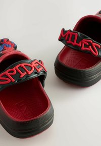 Zoccoli per bambini rossi e neri con cinturini goffrati "SPIDEY" e "MILES", featuring una grafica di Spider-Man sulla parte anteriore e una soletta testurizzata.