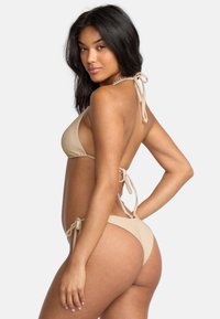 Beżowy bikini w prążki z regulowanymi zapięciami na szyi i plecach. Oferuje minimalne zasłonięcie i gładką, jednolitą fakturę.