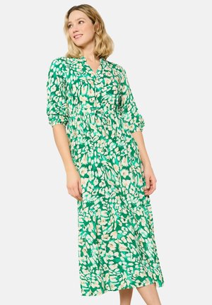 Robe midi verte à imprimé floral dans des tons de crème et de vert foncé, avec un devant à boutons, une taille froncée et des manches bouffantes.