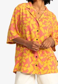 Short-sleeve button-up shirt in a pink and yellow floral pattern, made of a lightweight fabric, featuring a collar and relaxed fit.