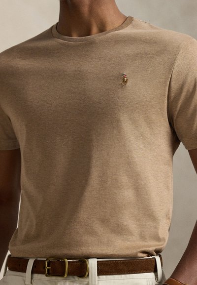 Trumpomis rankovėmis smėlio spalvos marškinėliai iš minkštos medžiagos su apvalia iškirpte, krūtinėje esančiu mažyčiu siuvinėtu logotipu ir lygiu paviršiumi.