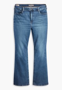 Ljust blå denim med utställda ben och medelhög midja, med fem fickor, subtila blekningar och kontrasterande sömmar längs sömmarna.