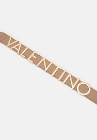 Läderbälte i tan med framträdande, guldtonade bokstäver som stavar "VALENTINO" och en rund accent, vilket framhäver eleganta, moderna designelement.