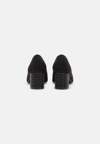 Scarpe in suede nero con punta affusolata e tacco quadrato testurizzato caratterizzato da un motivo a griglia. Il tacco offre stabilità e altezza.