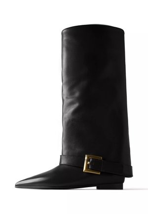 Tall black leather boot with a pointed toe and a leather strap with a large gold buckle around the ankle area, side view.
