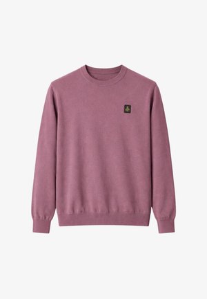 Maglione color malva a maniche lunghe con scollo rotondo, polsini e orlo a coste, con una piccola toppa quadrata nera con emblema dorato sul petto a sinistra.