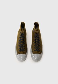 Olivovo zelené vysoké tenisky s šedými gumovými špičkami, čiernymi šnúrkami a textilným povrchom. Čistý dizajn s minimálnym brandingom.