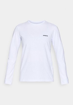 T-shirt en coton blanc à manches longues avec un col rond et le logo "patagonia" noir sur la poitrine gauche. Texture lisse, coupe classique.