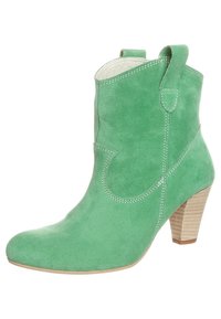 Bottine en daim vert avec un bout pointu, des coutures décoratives et un talon empilé. Comprend des languettes pour un enfilage facile.