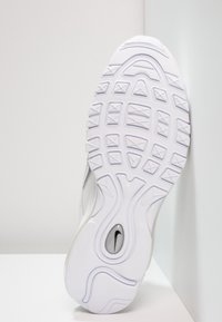 Semelle d'une chaussure de sport blanche avec une semelle texturée et un petit logo Nike noir visible près du talon.