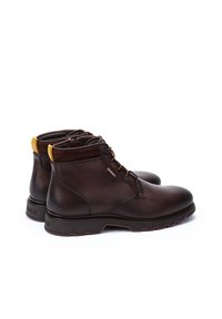 Brown leather ankle boots with a smooth finish, featuring yellow accents, lace-up front, and rugged rubber sole for traction.