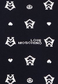 Mörk tyg med ett upprepat mönster av vita logotyper, hjärtan och fredssymboler, med texten "LOVE MOSCHINO" tydligt framhävd.
