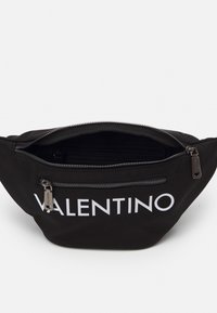 Schwarze Stoffgürteltasche mit weißem "VALENTINO"-Logo, ausgestattet mit einem Reißverschluss und einer Innentasche. Glatte Textur, elegantes Design.