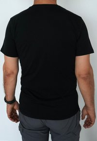 Schwarzes Baumwoll-T-Shirt mit kurzen Ärmeln und Rundhalsausschnitt, das eine glatte Textur und eine taillierte Passform aufweist, von hinten gezeigt.
