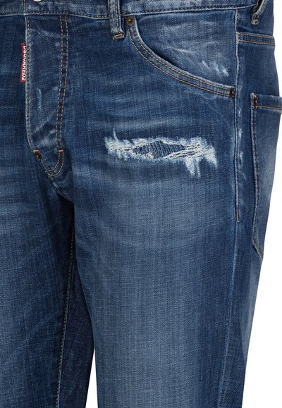 Blue denim jeans with a faded and distressed patch on the right thigh and visible orange stitching near pockets.
