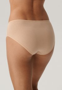 Beżowe majtki bawełniane z mieszanką materiałów, bezszwowe wykończenia, średni stan i gładka tekstura. Posiadają wyprofilowane plecy dla większego komfortu.