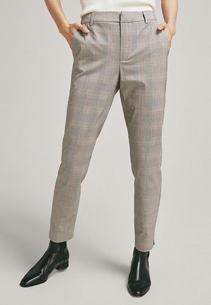 Graue karierte Hose mit schmaler Passform, seitlichen Taschen und glatter Textur, kombiniert mit schwarzen Stiefeletten.