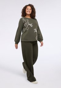 Olivově zelená mikina s květinovým konturovým designem, dlouhými rukávy a kulatým výstřihem, spojená s odpovídajícími olivově zelenými kalhotami širokého střihu.