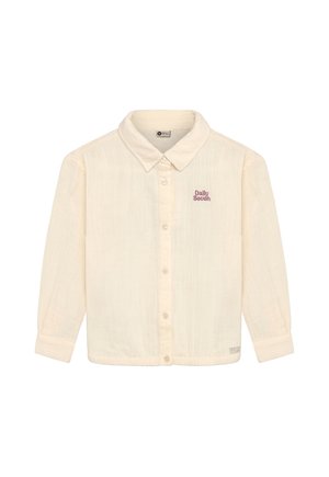 Beige langærmet skjorte med knapper og krave, broderet "Daily Seven" på venstre bryst og ærmer med manchetter.