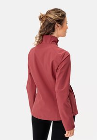 Giacca softshell rossa con colletto alto, design aderente e due tasche laterali. Tessuto liscio con dettagli di cuciture invisibili.