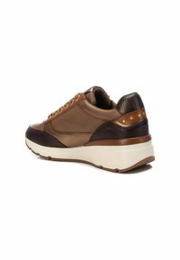 Zapatilla marrón y beige con un talón texturizado en marrón oscuro, tachuelas metálicas en los laterales y una entresuela blanca. Presenta una puntera redondeada y cierre de cordones.