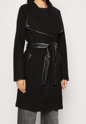 Black coat with a wrap design, featuring a leather belt and accents. Made from a textured fabric with a wide collar and side pockets.