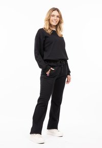 Felpa nera con una vestibilità comoda e scollo rotondo, abbinata a pantaloni della tuta neri coordinati, dotati di cordoncino regolabile e tasche.