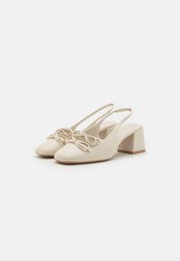 Pantofi slingback bej cu vârf ascuțit, având un detaliu sub formă de fundă în față și toc bloc. Textură netedă și design minimalist.