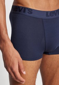 Tengerés kék pamut boxer alsónemű texturált derékrésszel, amelyen a Levi's logó található. Közeli kép az anyagról és a testhez való illeszkedésről egy modellen.