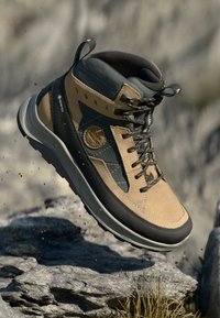Smešano smeđe i sive planinarske čizme od GORE-TEX materijala, s visokim gležnjem, teksturiranim stranama, vezanjem na vezice i gumiranim đonom.