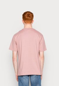 T-shirt di cotone rosa chiaro con maniche corte e scollo rotondo, vista dal retro, con una vestibilità morbida e una consistenza liscia.
